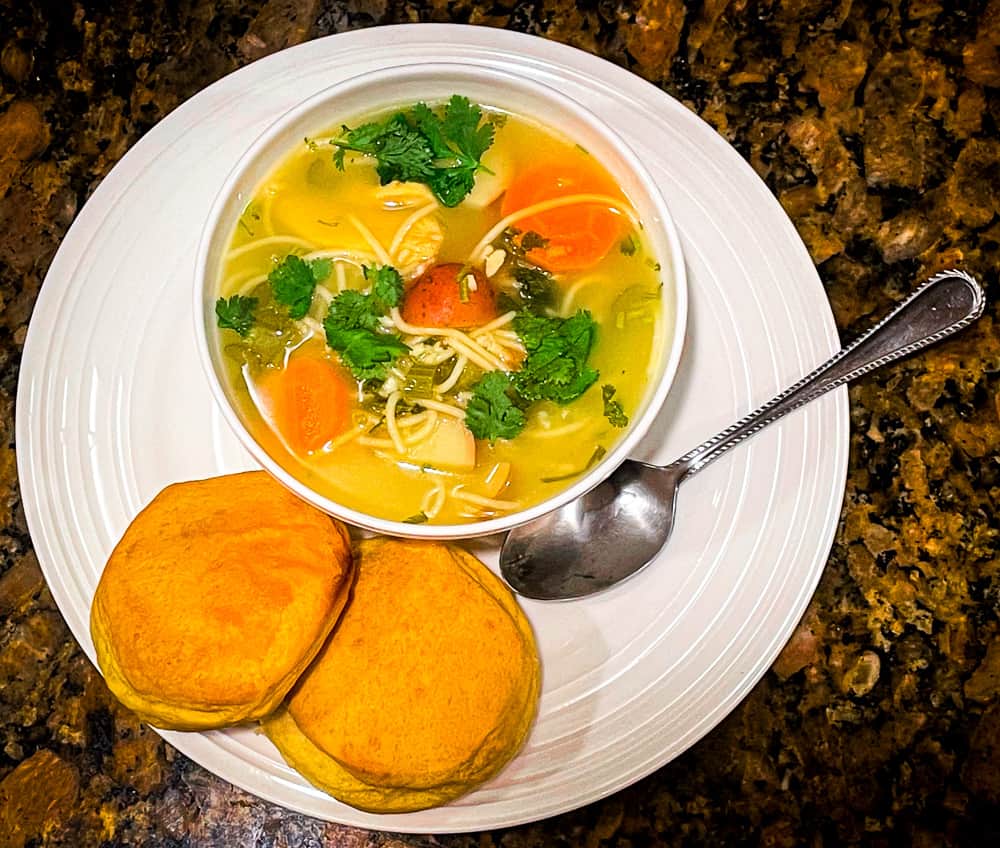 Lime and Cilantro Chicken Noodle Soup in a bowl with oven-baked biscuits.