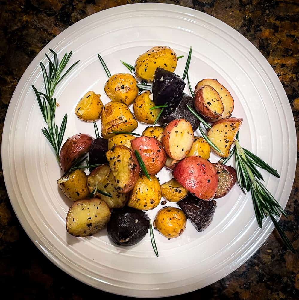 Rosemary and Garlic Roasted Potatoes on a plate and garnished with fresh rosemary sprigs. 