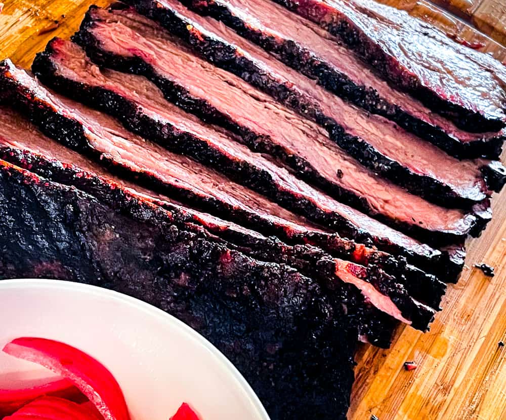 Sliced Texas-style smoked brisket with pickled onions.